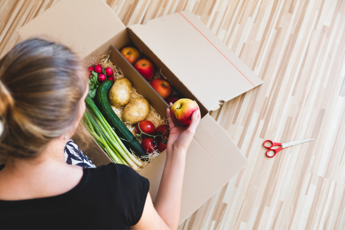 Woman opening subscription grocery box.